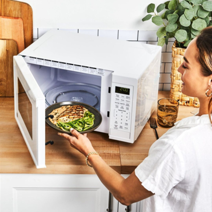 Woman putting a meal into a microwave